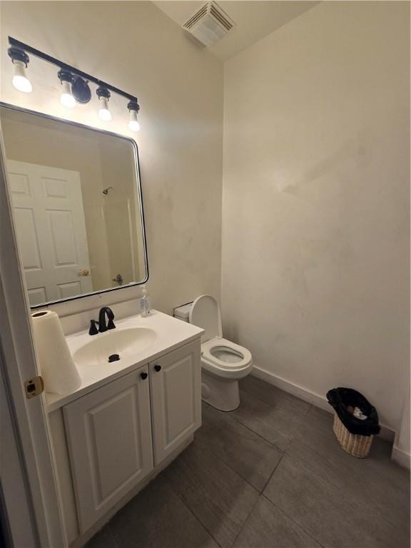 bathroom with toilet, vanity, visible vents, tile patterned floors, and baseboards