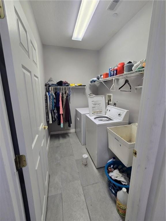 laundry room with a sink, laundry area, visible vents, baseboards, and independent washer and dryer