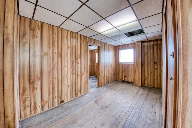 spare room featuring a drop ceiling, hardwood / wood-style floors, and wooden walls