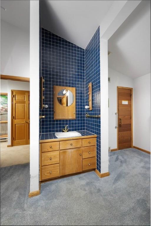 bathroom with baseboards, vanity, and vaulted ceiling