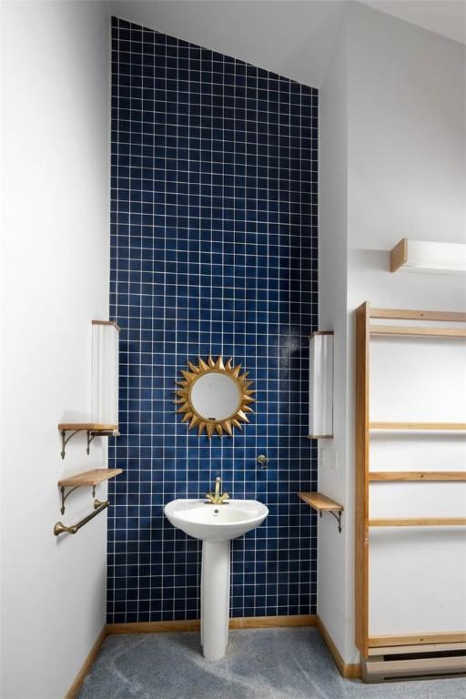 bathroom with a sink, tile walls, baseboards, and a baseboard heating unit