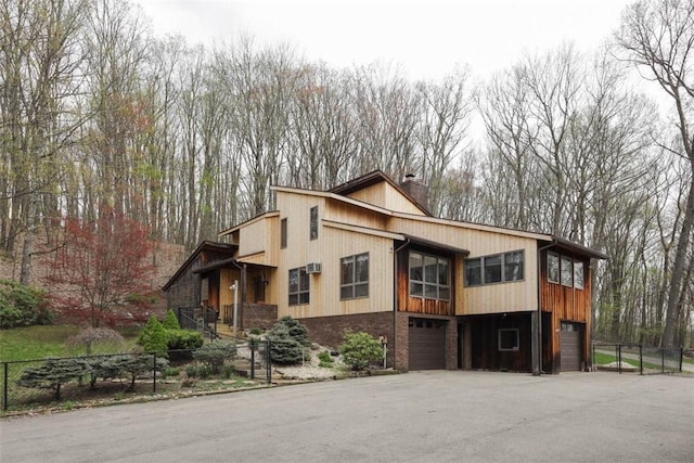 view of front facade featuring an attached garage, a chimney, and fence