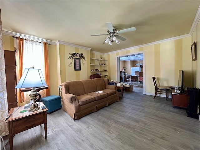 living area with crown molding, light wood-style flooring, baseboards, and ceiling fan