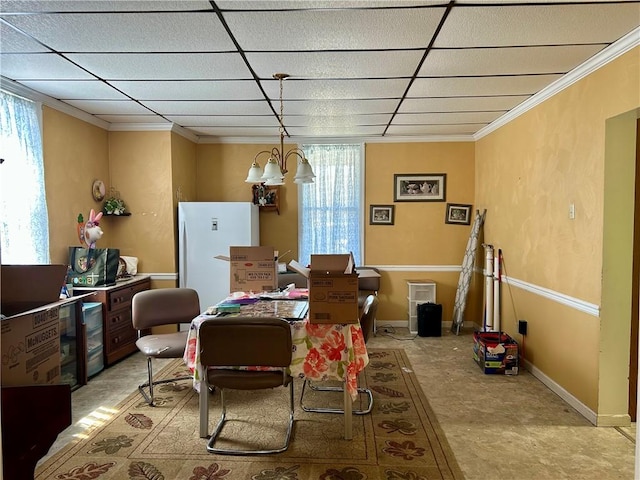 dining area with baseboards, a paneled ceiling, a chandelier, and crown molding
