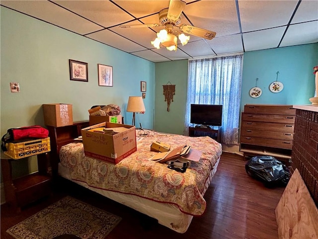 bedroom with wood finished floors, a ceiling fan, and a paneled ceiling