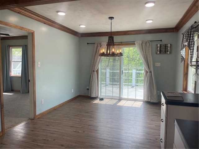 unfurnished dining area with baseboards, ornamental molding, an inviting chandelier, and dark wood-style floors