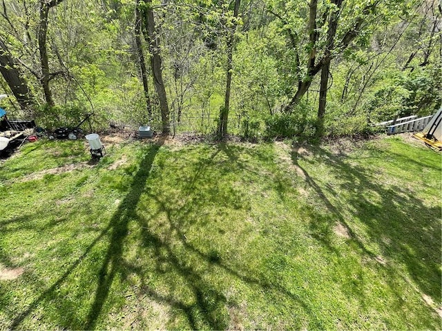view of yard featuring a wooded view and fence