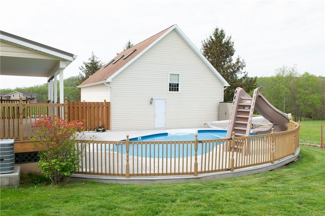 back of property with central air condition unit, a yard, a deck, and a fenced in pool