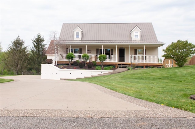 farmhouse featuring a storage shed, covered porch, metal roof, an outdoor structure, and a front yard