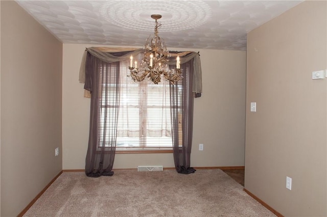 spare room with a textured ceiling, baseboards, visible vents, a chandelier, and carpet floors