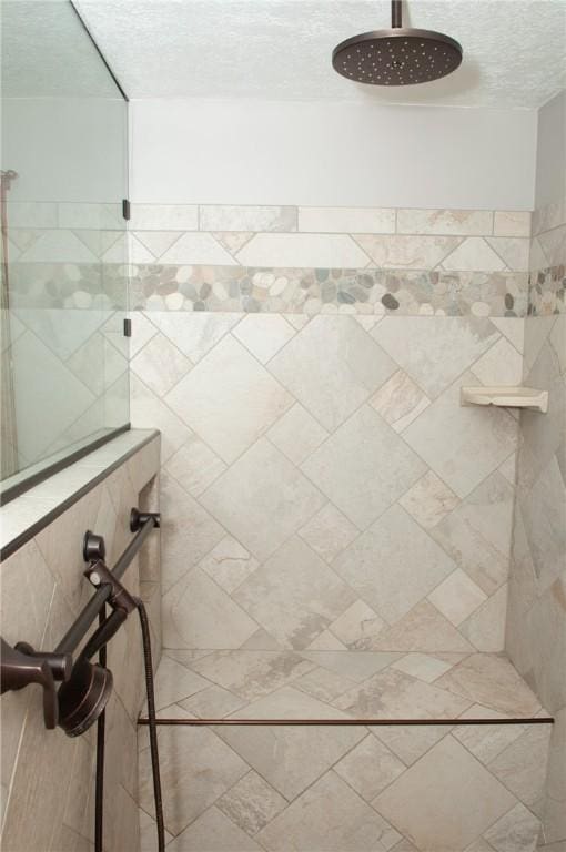 bathroom with a textured ceiling and a tile shower