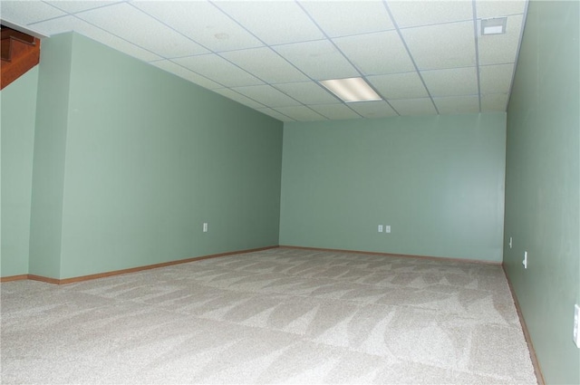 empty room featuring a paneled ceiling, light carpet, and baseboards