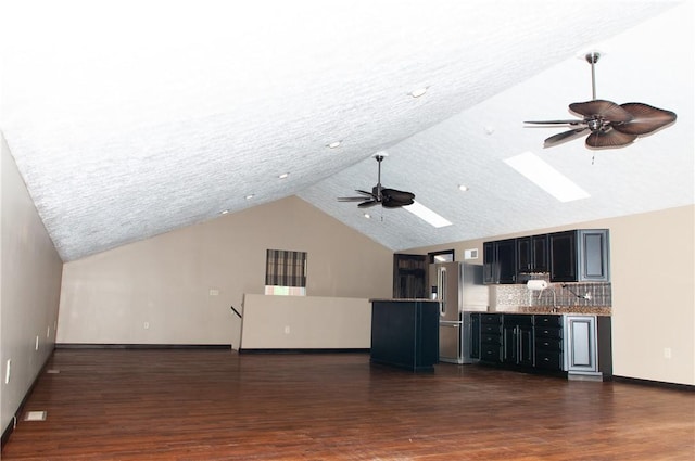 unfurnished living room with a ceiling fan, dark wood-style floors, baseboards, high vaulted ceiling, and a skylight