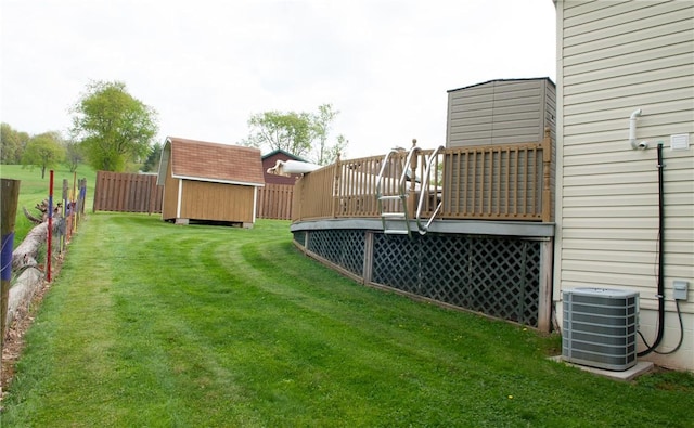 view of yard featuring fence, cooling unit, an outdoor structure, a wooden deck, and a storage shed