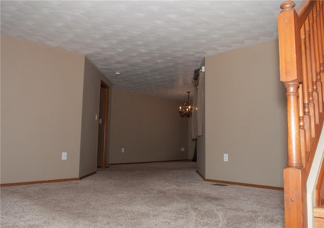 carpeted empty room featuring baseboards, stairway, and a chandelier