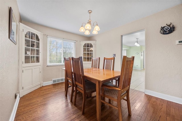 110 Thorncrest Dr, Penn Twp But, PA 16002 - dining room featuring wood finished floors, baseboards, visible vents, a textured wall, and a notable chandelier