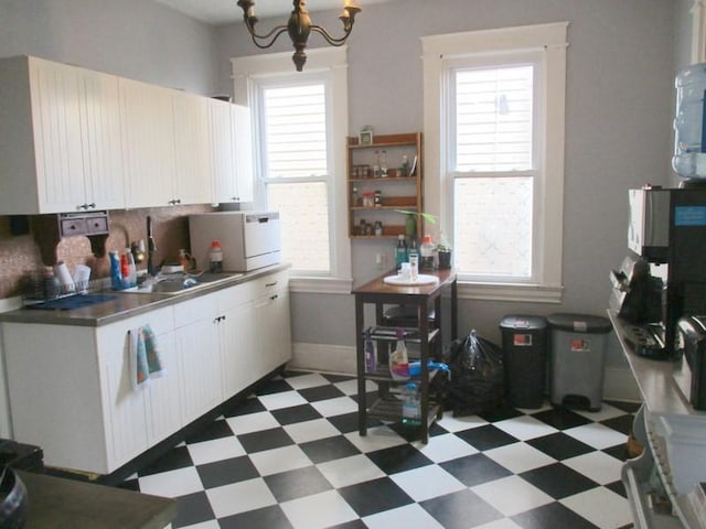 400 12th St, New Brighton, PA 15066 - kitchen with a sink, light floors, decorative backsplash, white cabinets, and a notable chandelier
