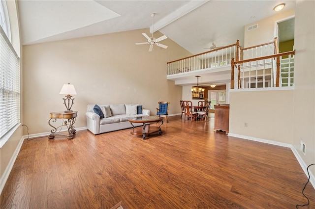 living area with high vaulted ceiling, beamed ceiling, a ceiling fan, wood finished floors, and baseboards