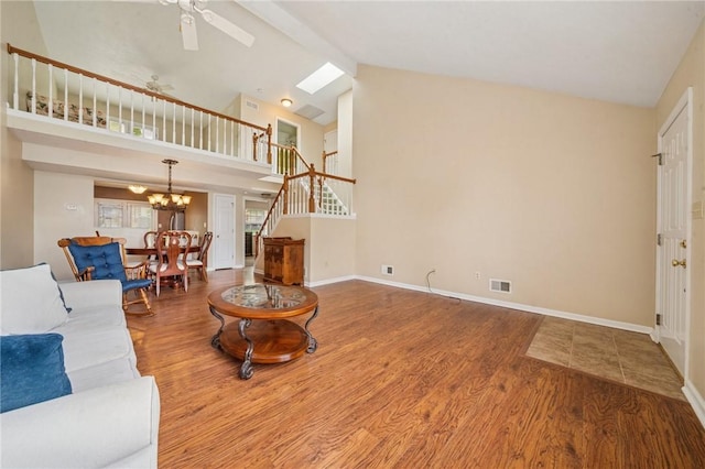 living room with wood finished floors, a chandelier, ceiling fan, high vaulted ceiling, and stairway