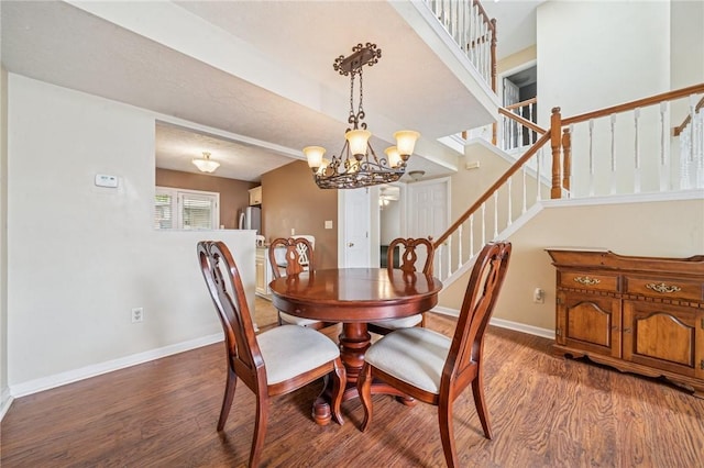 dining area with wood finished floors, a chandelier, baseboards, and stairs