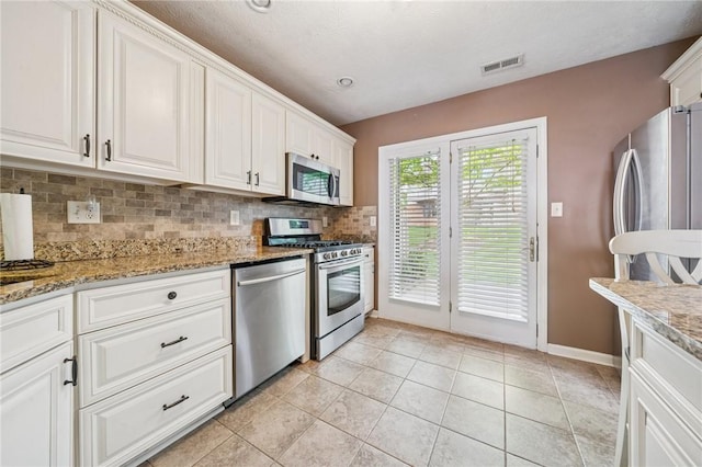 kitchen with appliances with stainless steel finishes, decorative backsplash, white cabinetry, and baseboards