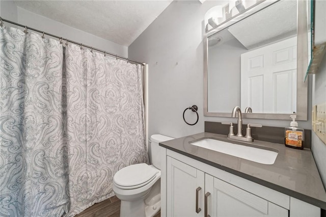 bathroom with toilet, vanity, wood finished floors, a textured ceiling, and curtained shower