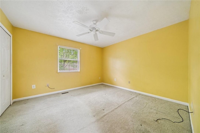 carpeted empty room featuring baseboards and a ceiling fan