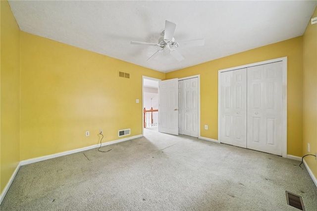 unfurnished bedroom featuring two closets, carpet, and baseboards