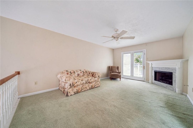 living area featuring carpet floors, ceiling fan, a fireplace, and baseboards