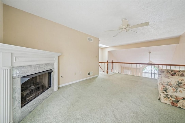unfurnished living room featuring a ceiling fan, carpet flooring, a high end fireplace, and baseboards