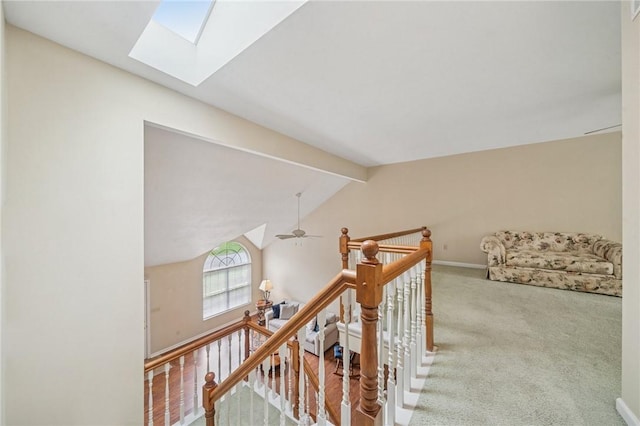 hall with an upstairs landing, a skylight, carpet flooring, and baseboards