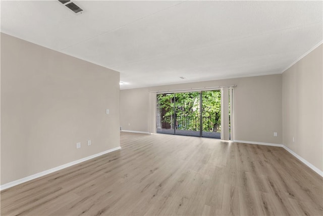 empty room featuring light wood finished floors, ornamental molding, baseboards, and visible vents