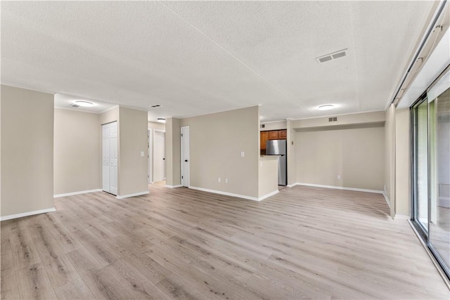 unfurnished living room featuring a textured ceiling, baseboards, visible vents, and light wood-style floors