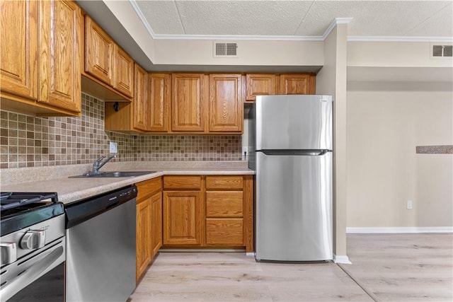 kitchen featuring visible vents, a sink, crown molding, light countertops, and appliances with stainless steel finishes