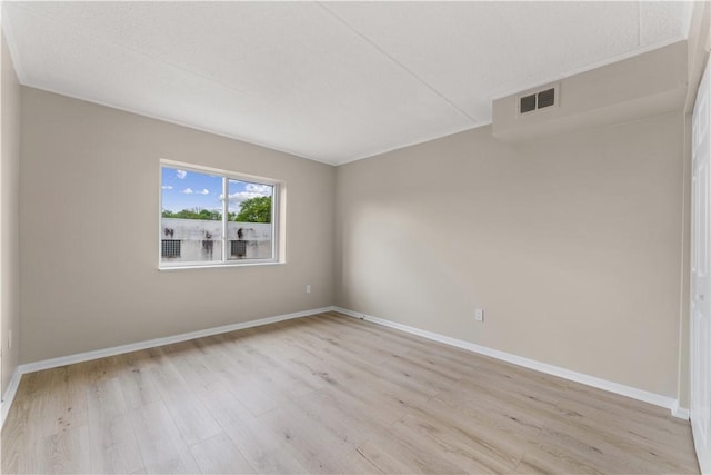 spare room with baseboards, light wood-type flooring, and visible vents