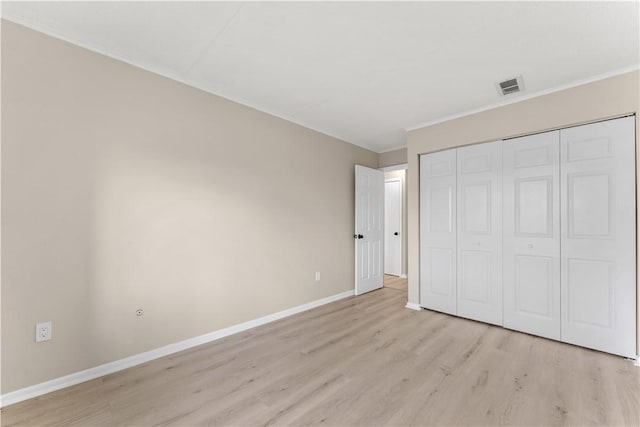 unfurnished bedroom with light wood finished floors, a closet, visible vents, baseboards, and ornamental molding