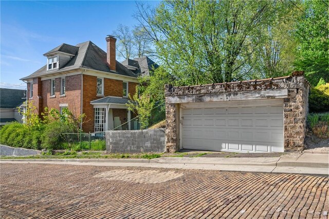 301 N Monroe St, City Of But Ne, PA 16001 - view of front facade with a chimney, brick siding, a garage, and fence