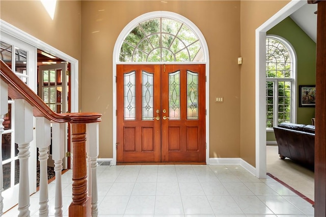 foyer entrance featuring baseboards, light tile patterned floors, and a high ceiling
