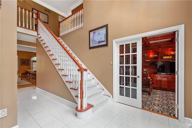 staircase featuring tile patterned floors, baseboards, and a high ceiling