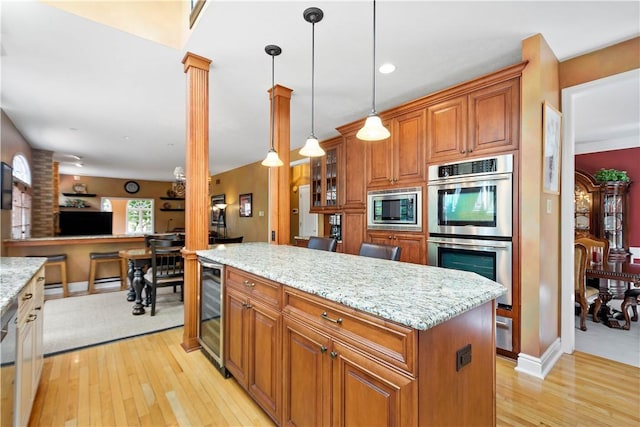 kitchen with light wood finished floors, stainless steel appliances, brown cabinetry, and beverage cooler