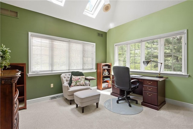 office space with carpet flooring, lofted ceiling with skylight, a healthy amount of sunlight, and visible vents