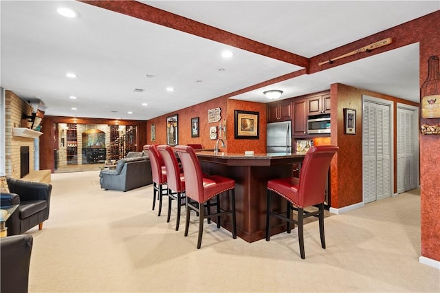 bar featuring indoor wet bar, stainless steel appliances, a brick fireplace, light carpet, and recessed lighting