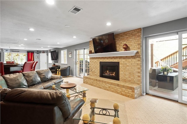 living area featuring carpet flooring, visible vents, a brick fireplace, and recessed lighting
