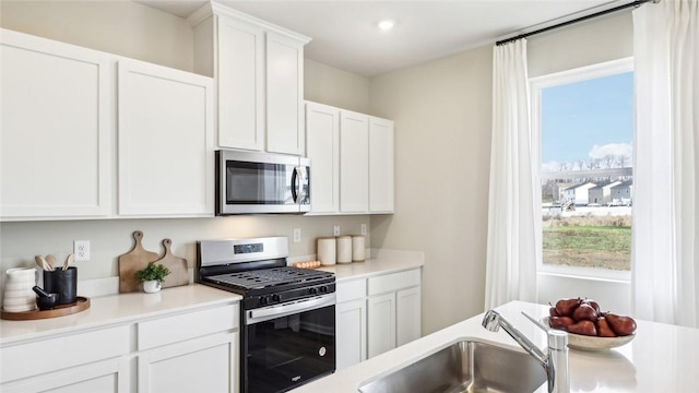 kitchen featuring light countertops, appliances with stainless steel finishes, a healthy amount of sunlight, and a sink