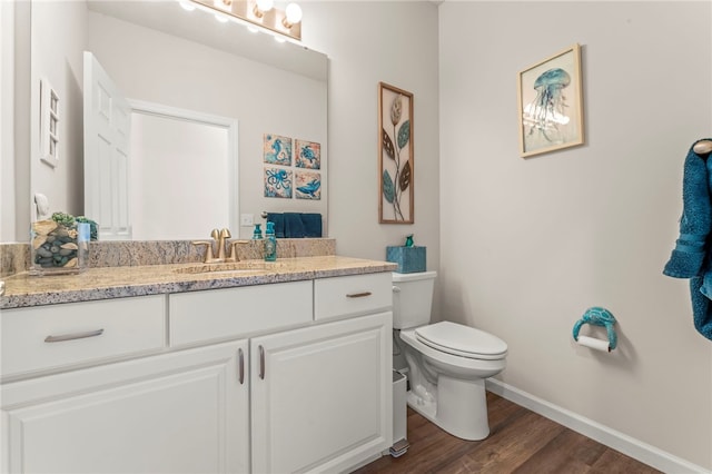 bathroom featuring vanity, toilet, wood finished floors, and baseboards