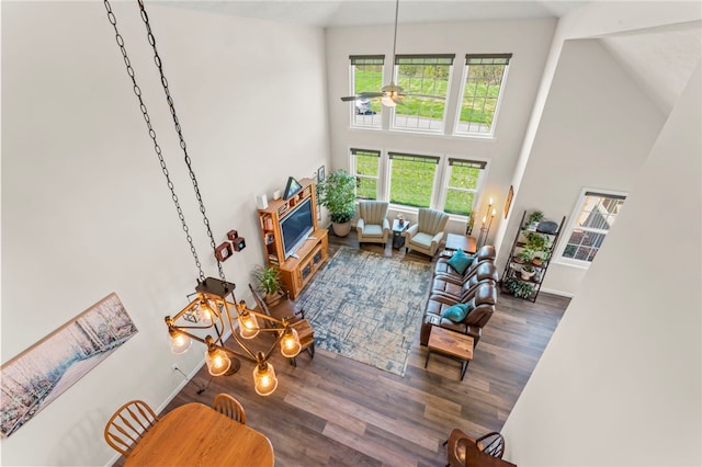 living area with ceiling fan, wood finished floors, and a high ceiling