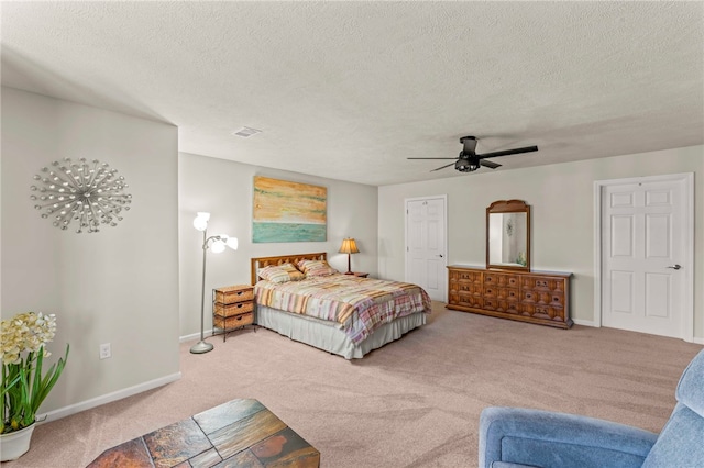 carpeted bedroom with a textured ceiling, visible vents, baseboards, and a ceiling fan