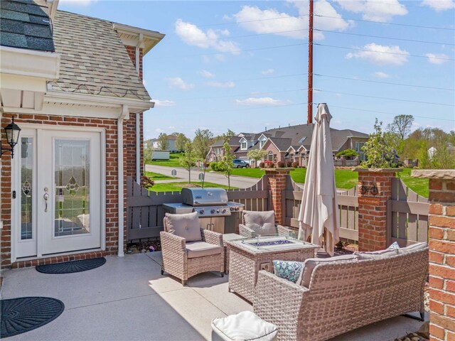 view of patio with a residential view, a fire pit, grilling area, and fence