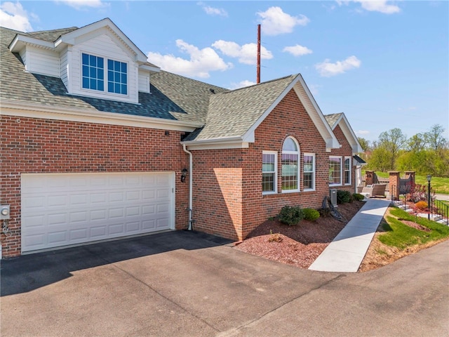 view of front of house featuring a garage, a shingled roof, brick siding, and driveway