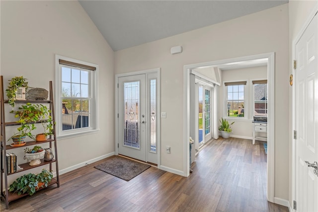 foyer entrance with baseboards, high vaulted ceiling, plenty of natural light, and wood finished floors